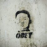 Graffiti on a gray wall of Kim Jong Un over the word Obey